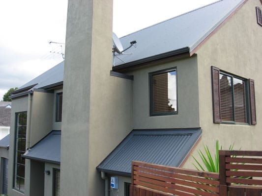 Modern two-storey house with a grey metal roof and smooth plastered exterior walls, showcasing professional roofing installation by Dr Roof New Zealand.
